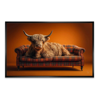 Brown and ginger Highland cow with horns on a fiery orange background on a plaid couch.
